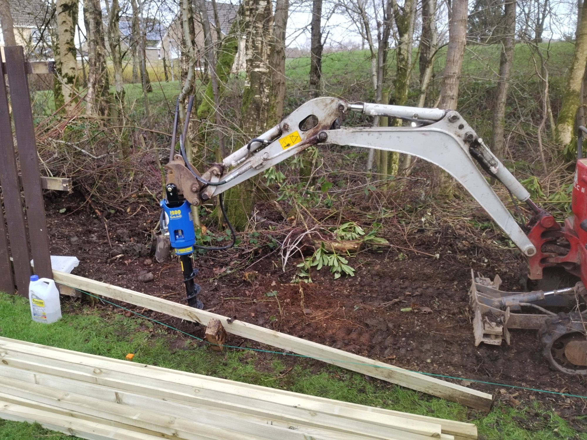 Small digger drilling out posts holes