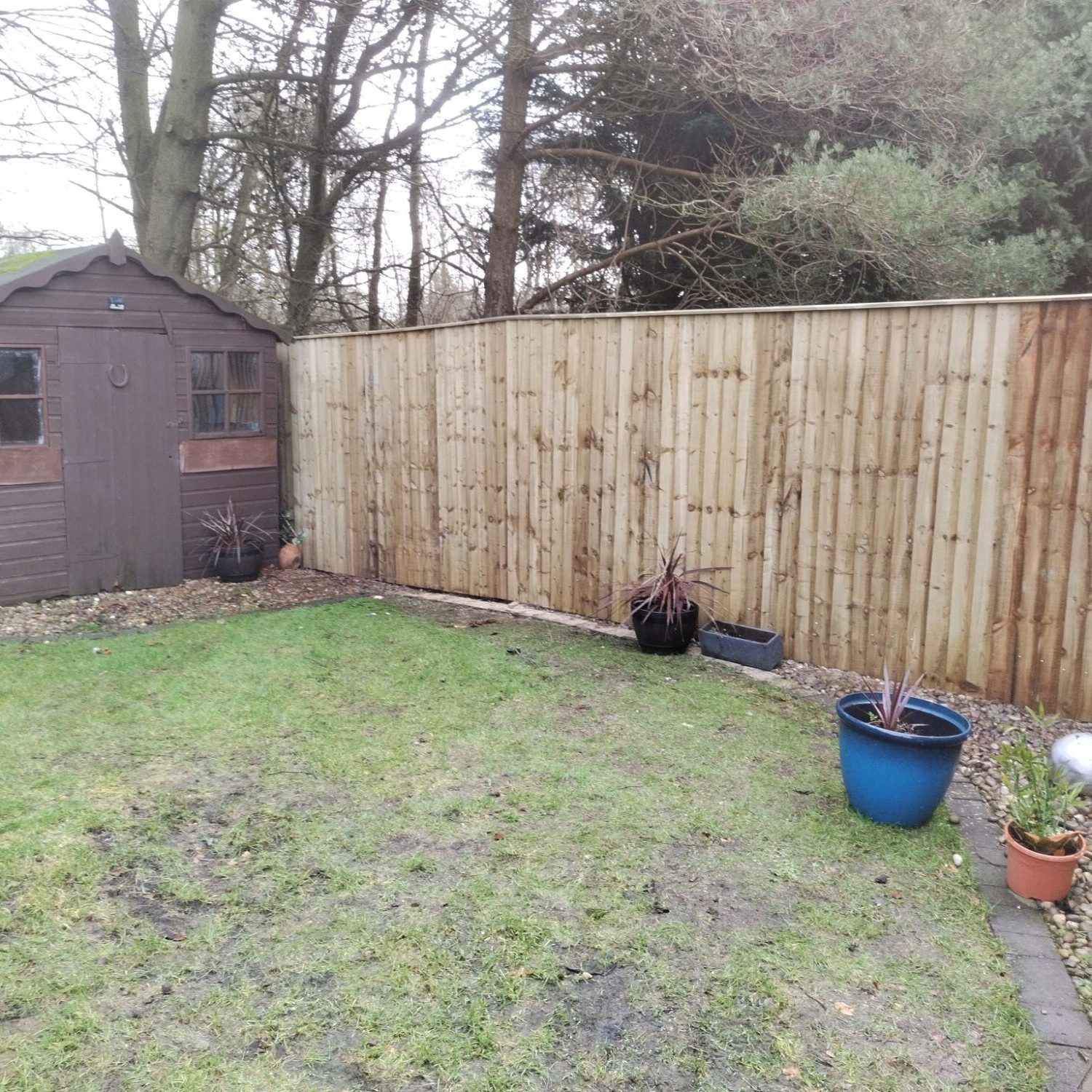 Long wooden fence with wooden garden shed